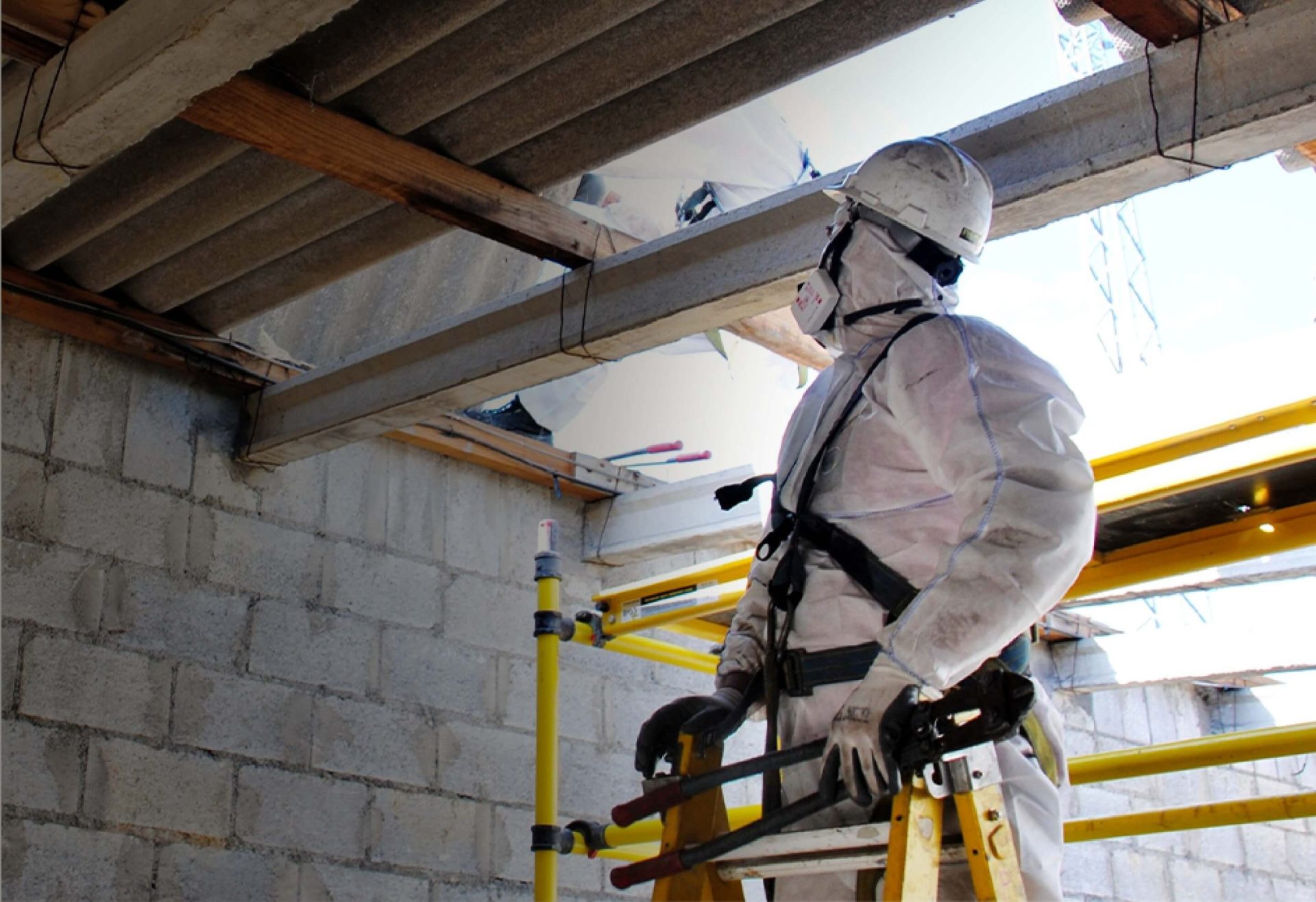 解体工事現場で作業服を着てヘルメットをつけた男性が上を見上げている写真