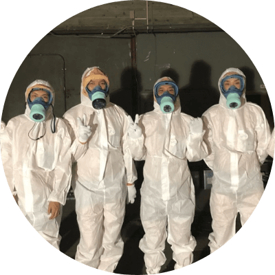防護服と防塵マスクをつけた男性が4人並んでいる写真