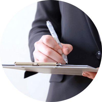 スーツを着た人が書類に書き込んでいる手元の写真