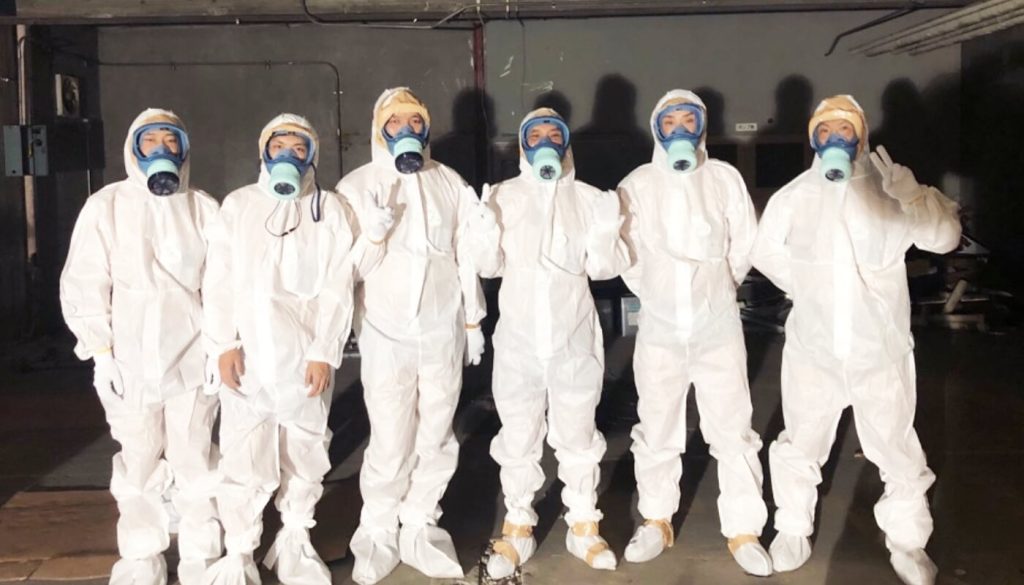 防護服と防塵マスクをつけた男性6人が並んでいる写真