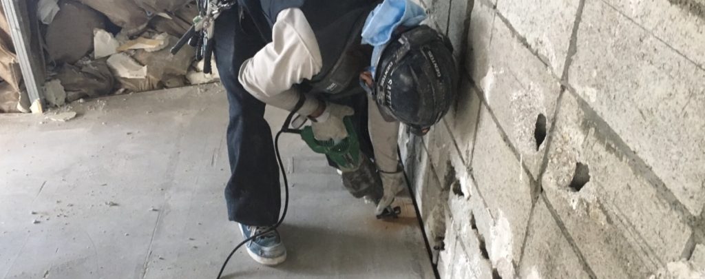 コンクリートの塀の近くで作業をしている男性